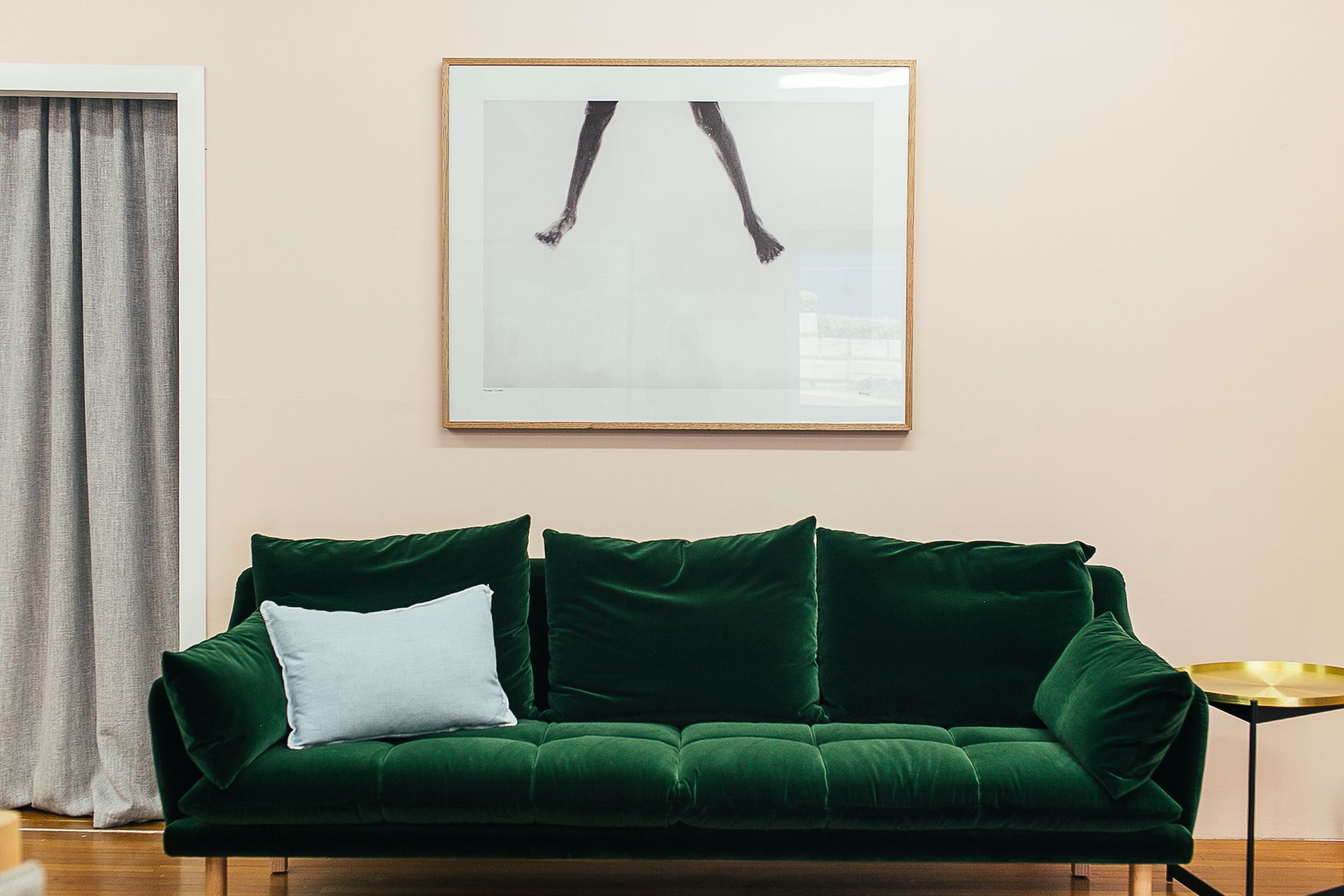 Green velvet sofa against a cream wall with framed art