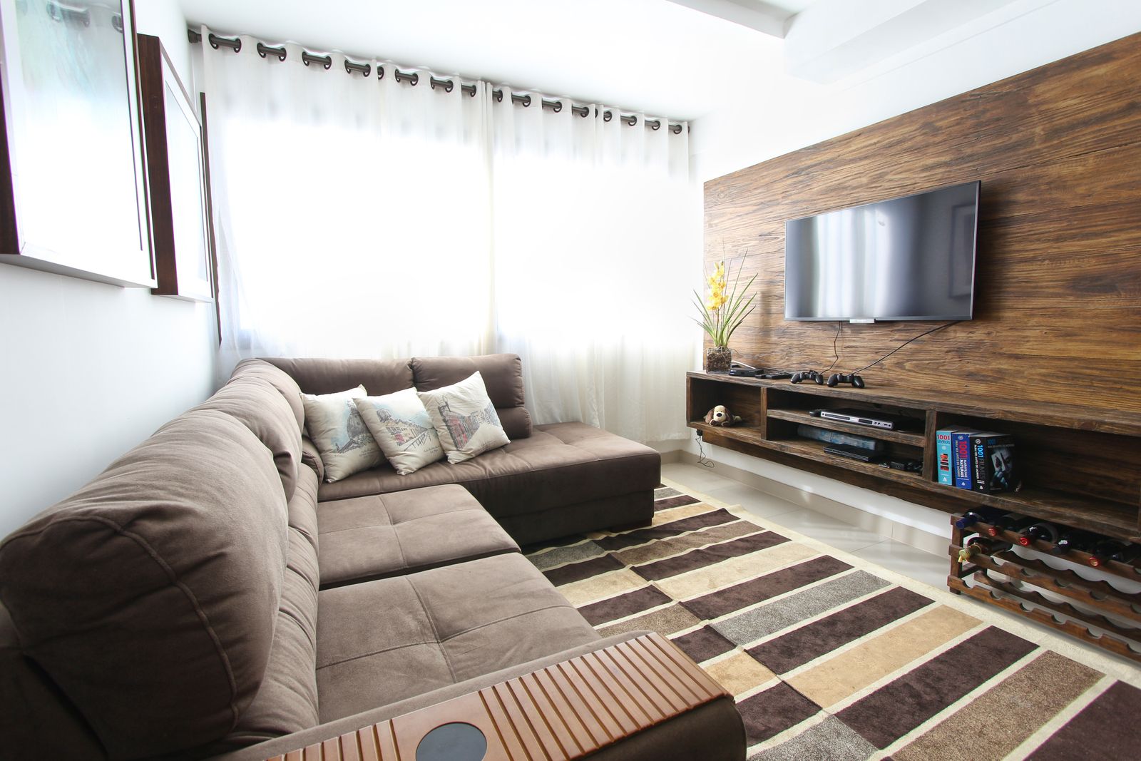 Living room with a brown sectional and warm wood wall